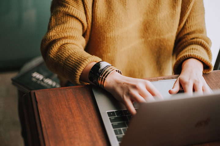 person in yellow sweater using a laptop